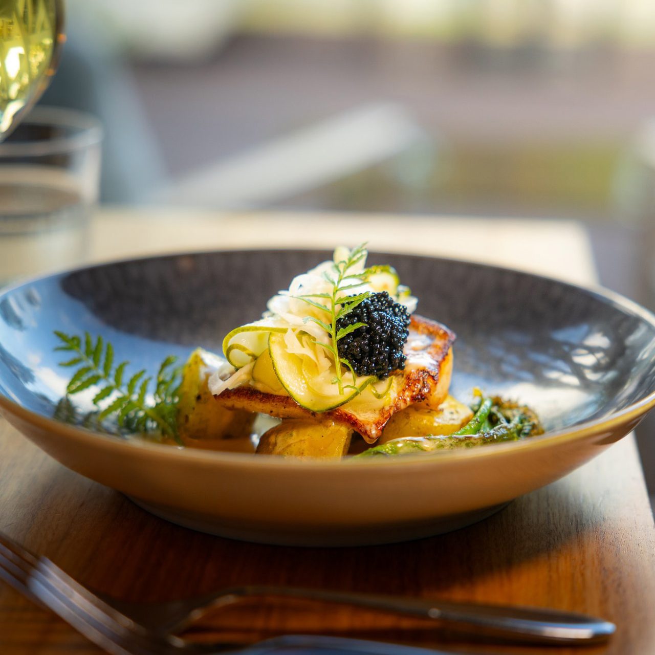 Autumn Flavour Journey at Rakas Restaurant – elegantly plated fish dish served with a glass of wine.