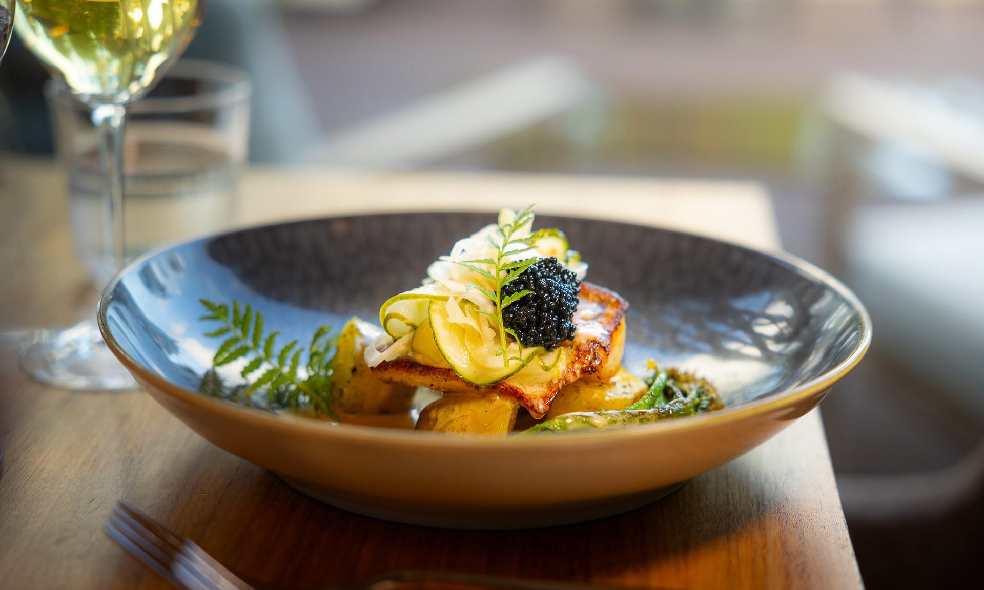 Autumn Flavour Journey at Rakas Restaurant – elegantly plated fish dish served with a glass of wine.