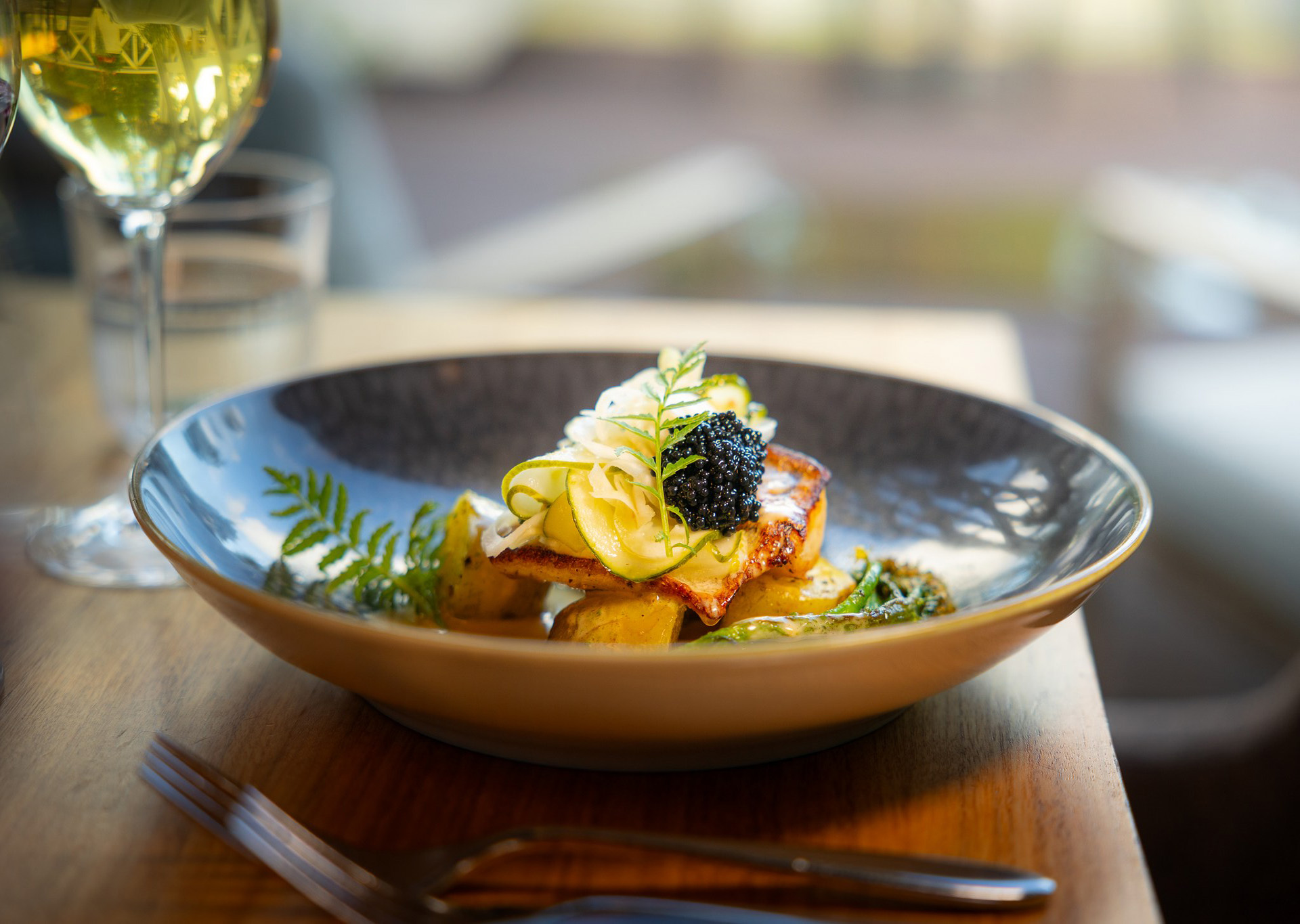 Autumn Flavour Journey at Rakas Restaurant – elegantly plated fish dish served with a glass of wine.